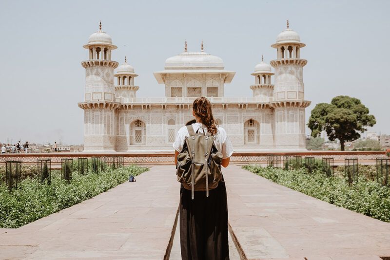 chica con mochila, de espaldas, mirando hacia un edificio en la india - weroad