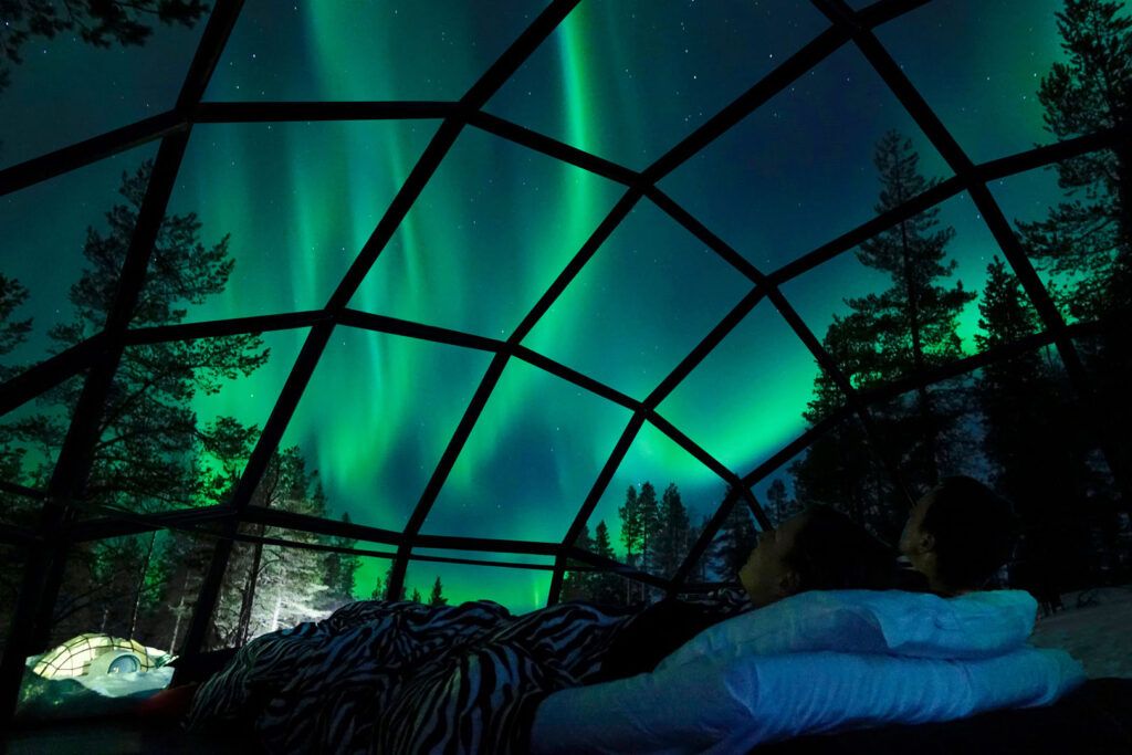 vista de la aurora boreal desde una habitación del igloo village que tiene techo de cristal - weroad