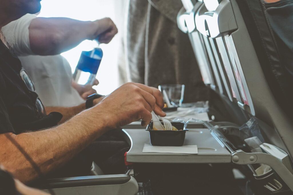 brazos de pasajero con cubiertos con delante comida en un avión - weroad