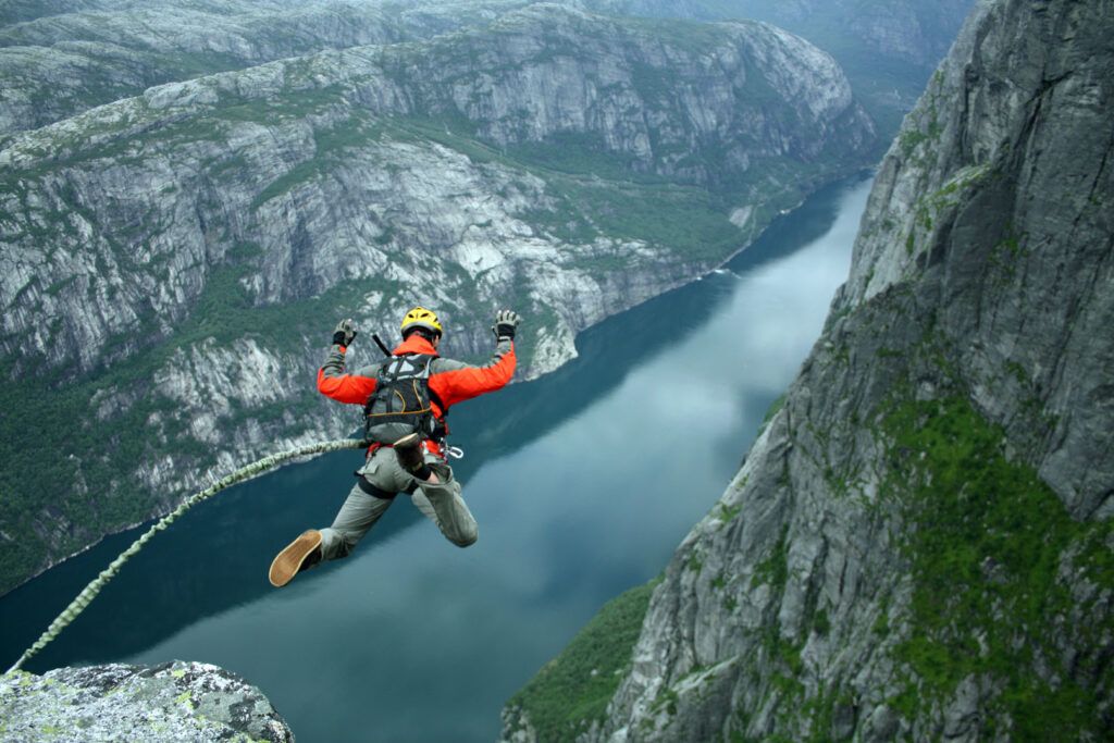 hombre saltando en bungee jumping en un paisaje de montañas y rio - weroad