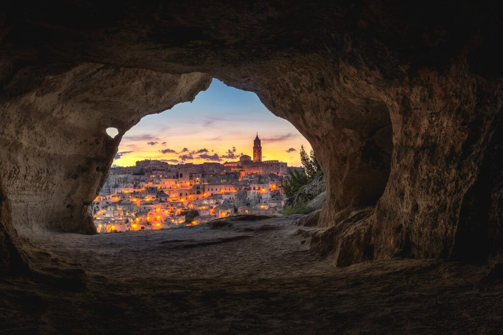 Un'apertura tra le rocce lascia intravedere la città di Matera al tramonto