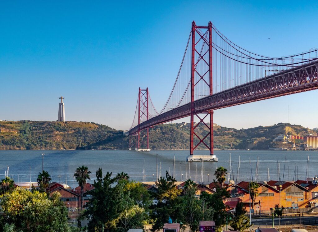 Il ponte 25 de Abril e la statua del Cristo Rei visti dalla riva del fiume Tago a Lisbona