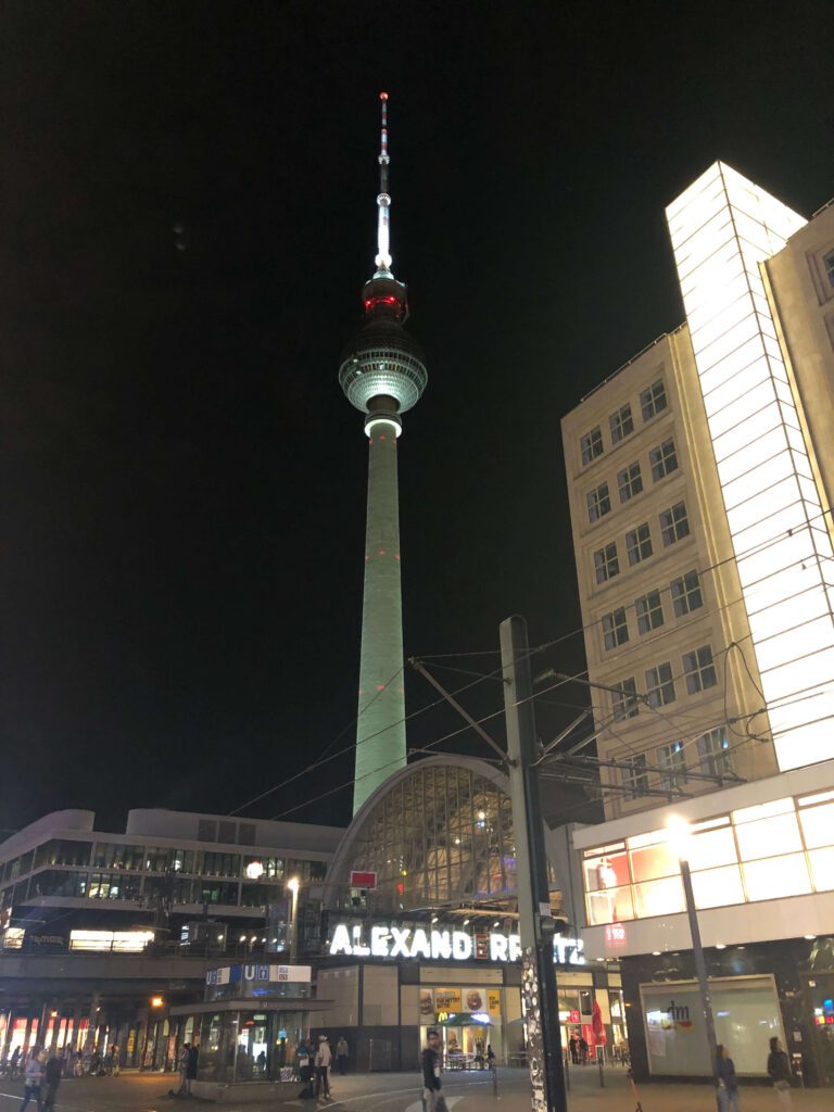 La torre della tv illuminata sovrasta AlexanderPlatz di notte.