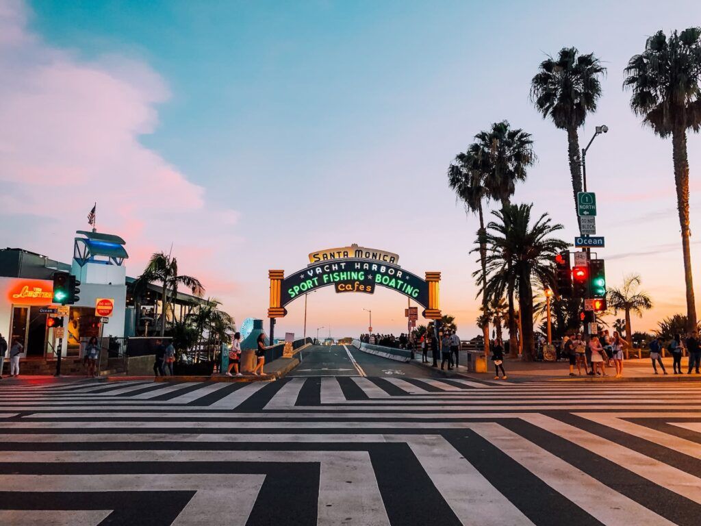 Alcune persone attraversano a strada sotto la scritta Santa Monica vista al tramonto