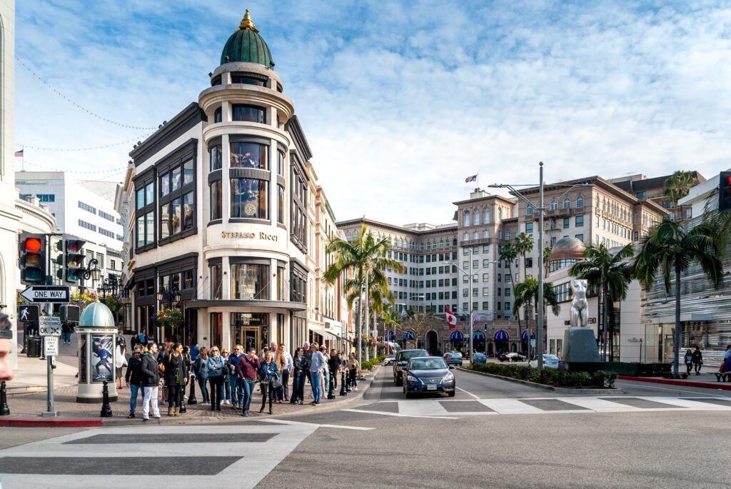Delle persone attraversano la strada davanti ai negozi di Beverly Hills durante il giorno