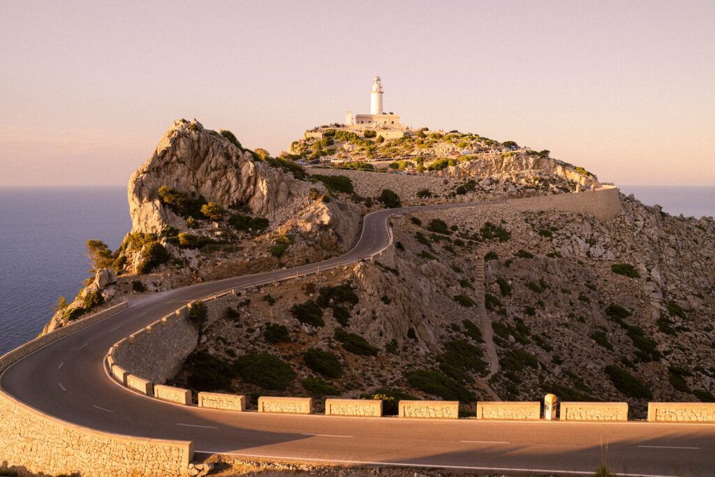 Una strada conduce al faro di Cap de Formentor sulle scogliere a picco sul mare al tramonto