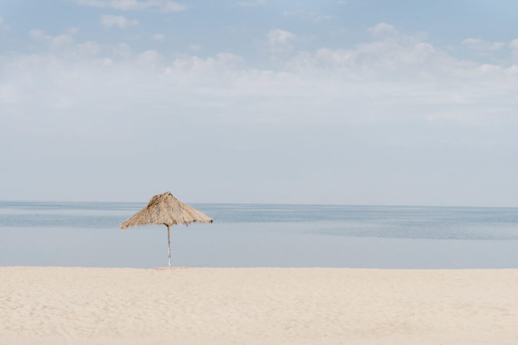 Un ombrellone di paglia sulla riva di sabbia bianca di fronte al lago Tanganica