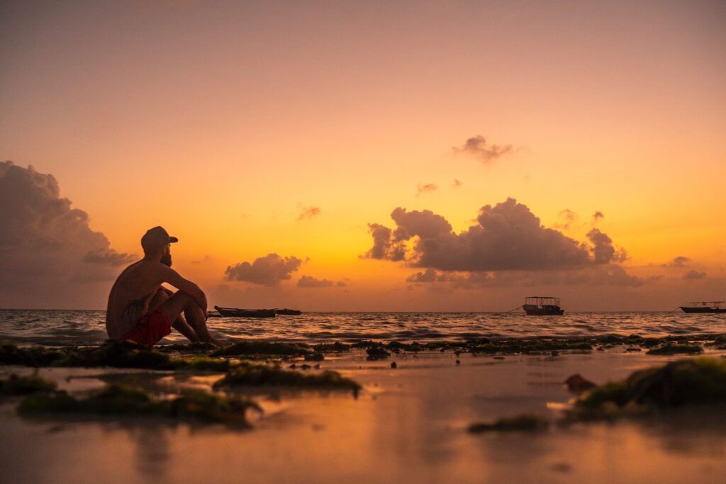 Un uomo osserva l'alba sulla spiaggia di Paje con la bassa marea