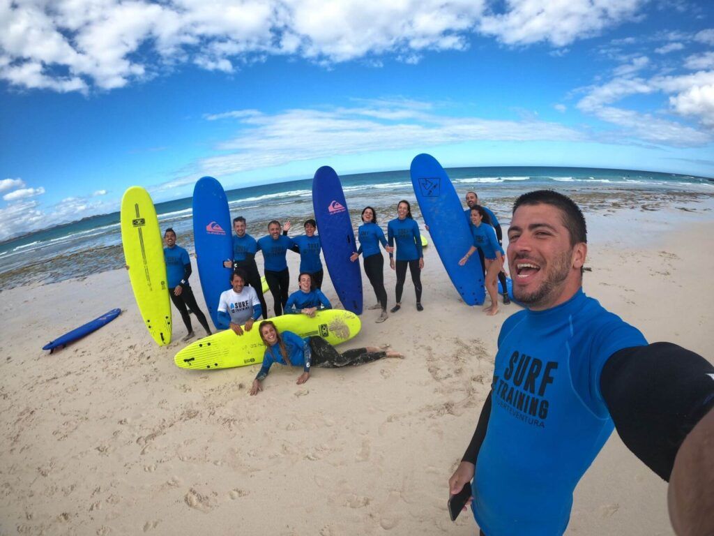 Uomo in primo piano con gruppo di persone in muta da surf al mare