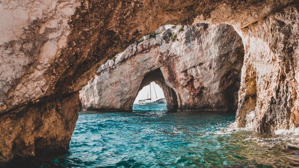 foto delle bellissime grotte blu di zante con una barca a vela in lontananza