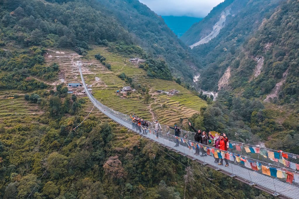 ragazzi che attraversano un ponte in nepal durante il trekking