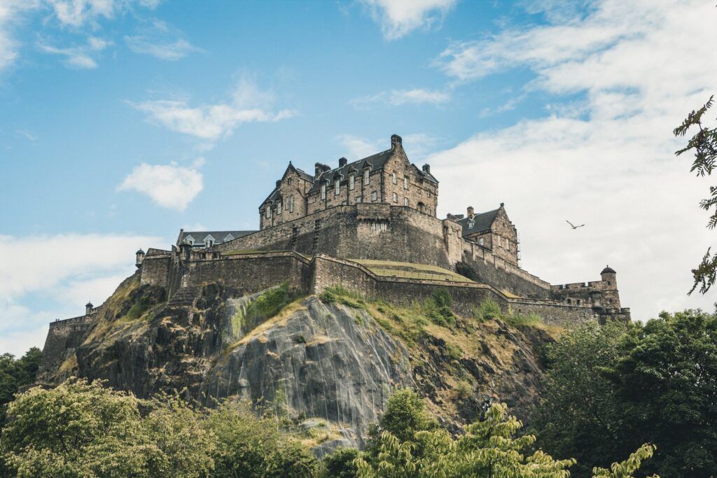 Il castello di Edimburgo in pietra grigia sembra fondersi con la roccia su cui sorge