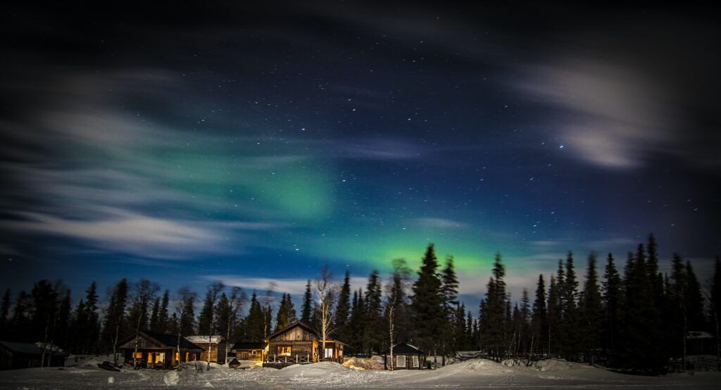 Casette in legno in mezzo alla neve con l'aurora boreale