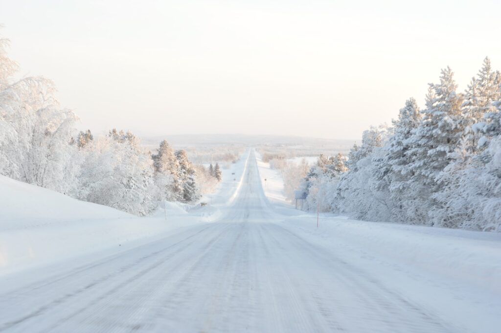 Una strada che si perde nel bianco della neve in Lapponia. Una delle avventure nel mondo da provare.