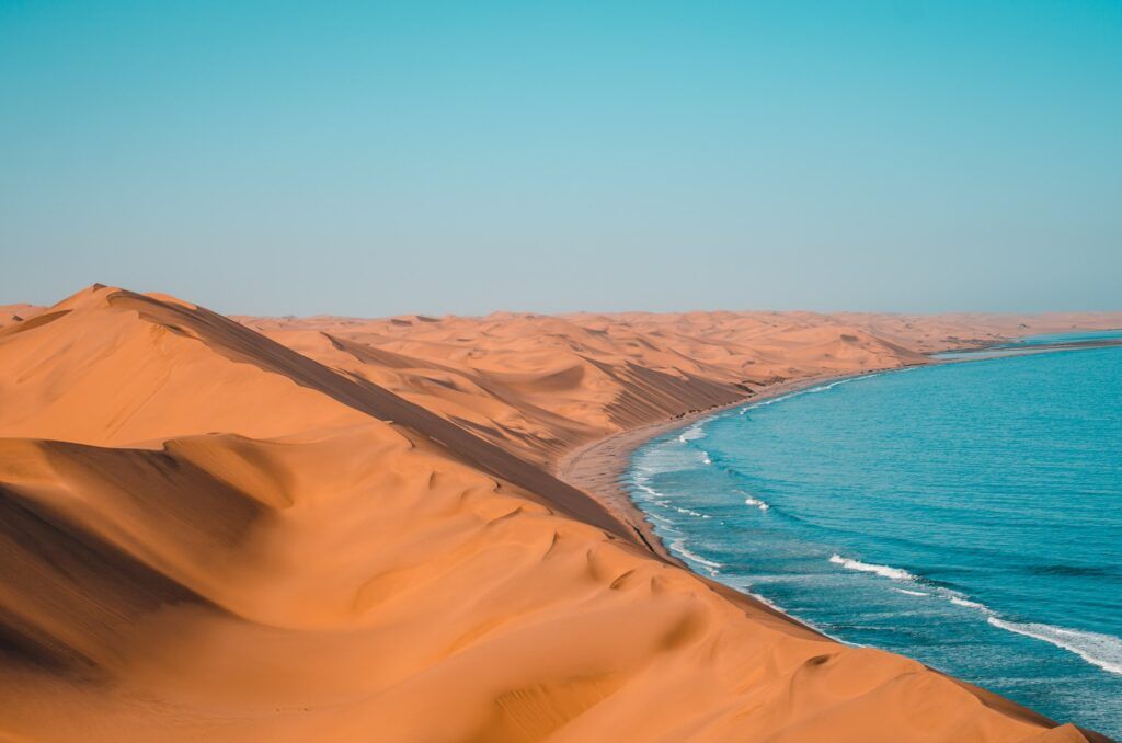 Vaste dune di sabbia si affacciano sul mare azzurro al tramonto