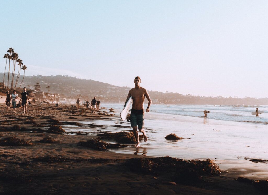 Un surfista cammina in spiaggia a San Diego