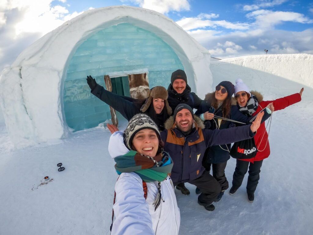 un gruppo di persone sorride davanti ad un igloo in Lapponia Svedese