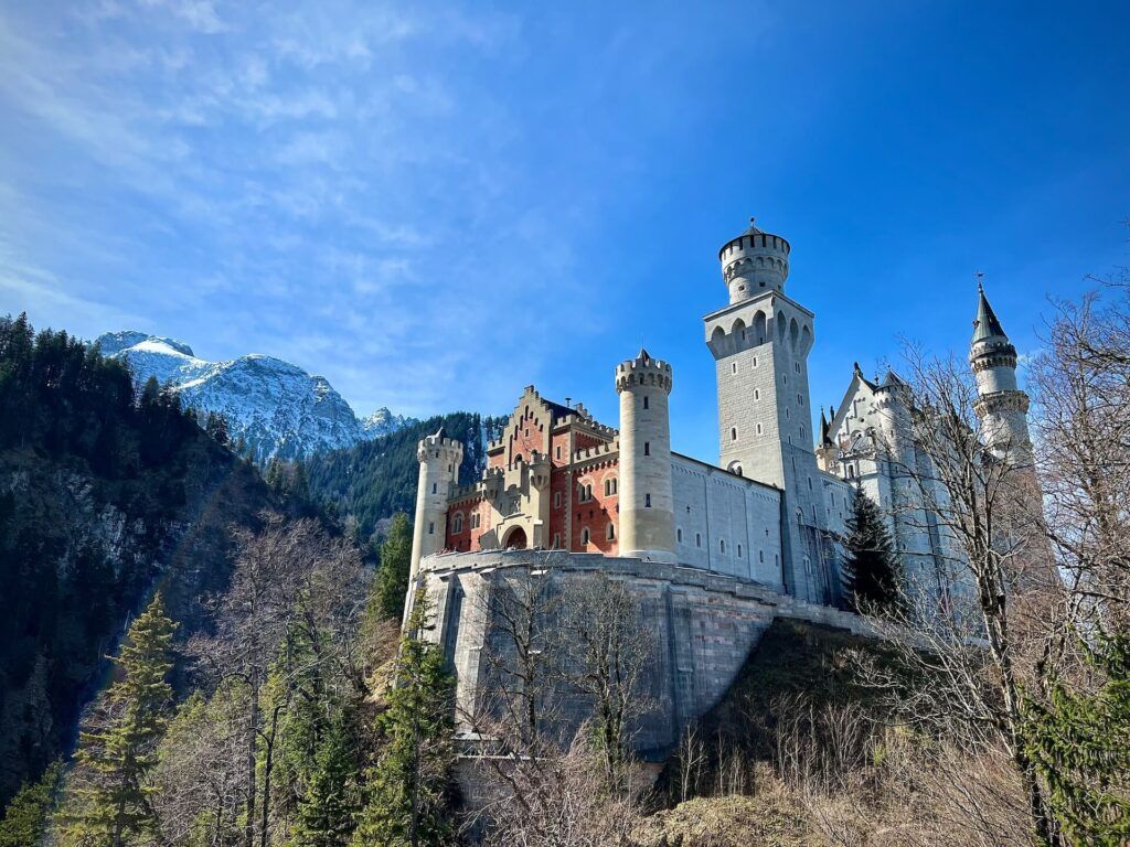 la magnifcenza del castello di Ludwig che si staglia davanti alle montagne in un giorno di sole