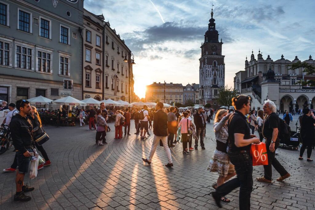 persone camminano in una piazza in Polonia al tramonto