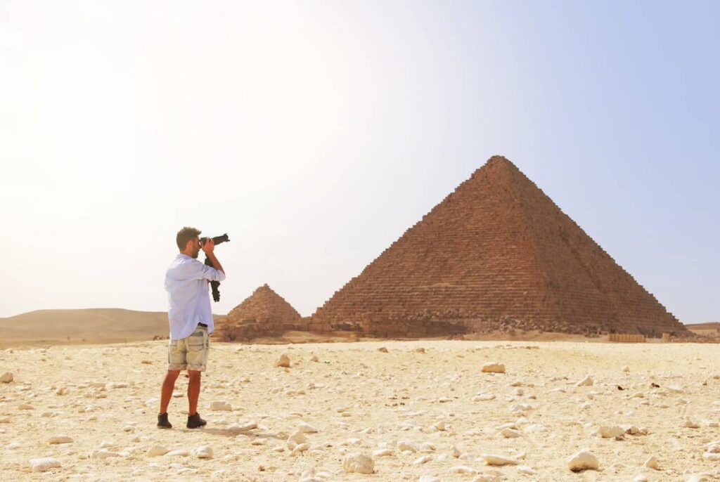 uomo vestito con abiti chiari fotografa le piramidi