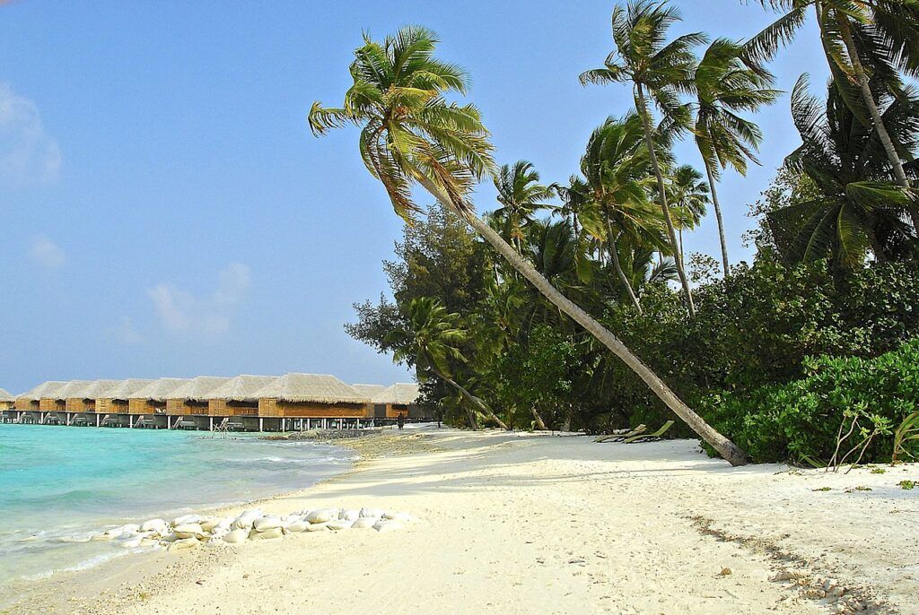 Spiaggia di sabbia dorata con bungalow sul mare nell'atollo di Kaafu