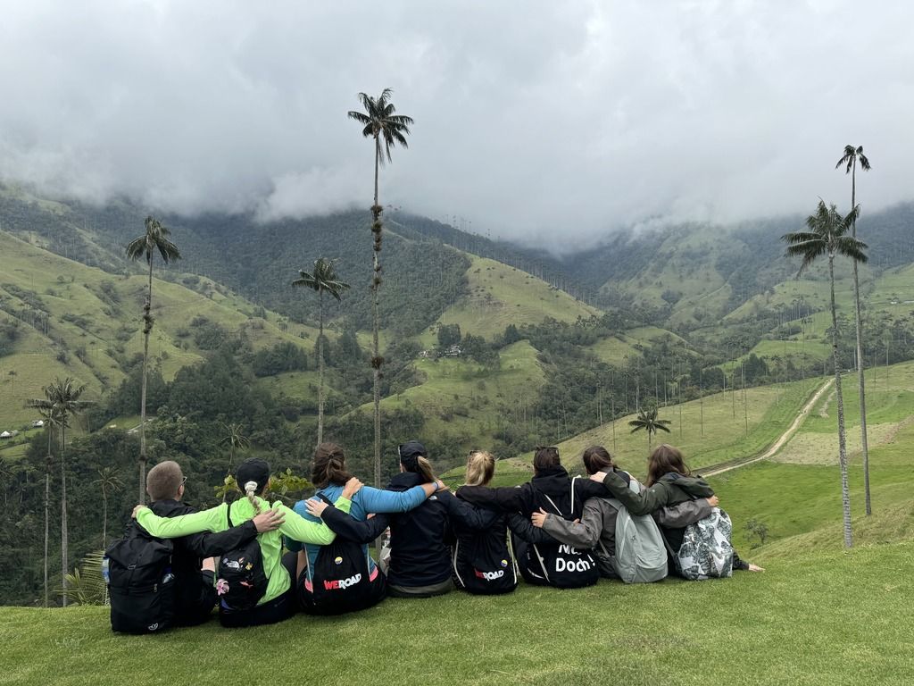 Abbracci tra compagni di viaggio nella Valle de Cocora, Colombia: palme, nuvole basse e amicizie che rendono il paesaggio ancora più magico.