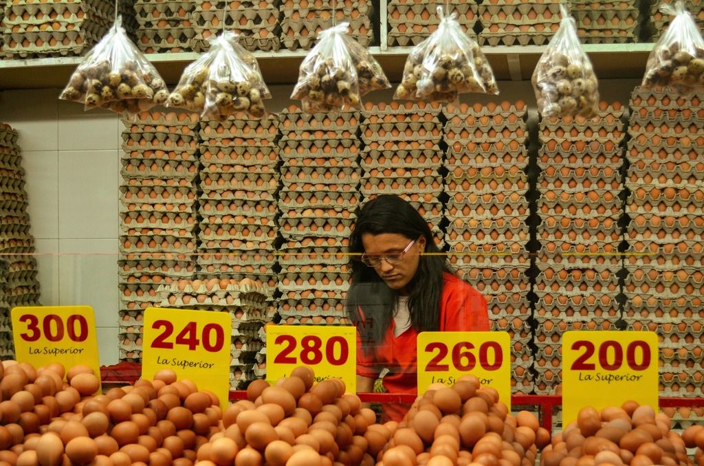 Banco delle uova in un mercato colombiano: tra prezzi colorati e file infinite di cartoni, un ritratto autentico della vita quotidiana nei mercati locali.