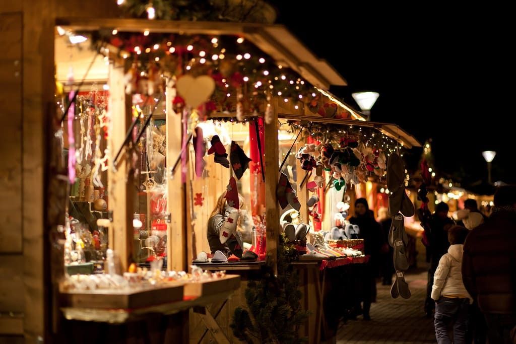 Mercatini di Natale a Merano di sera, tra bancarelle in legno e luci scintillanti.
